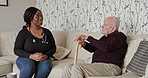 Woman, nurse and consulting senior patient on sofa with kane for healthcare, support or checkup at old age home. African female person, doctor or caregiver talking to elderly man on living room couch