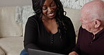 Senior, man and learning on laptop with caregiver in home with support and help in conversation. Happy, elderly person and black woman on sofa with technology, login or streaming web for social media
