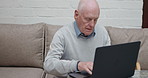 Home, laptop and senior man on a couch, typing and relax with connection, online reading and website information. Apartment, pensioner on a sofa and old guy with a computer and email notification