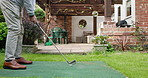 Golf, ball and man in backyard hitting for sports, training and relax with fun hobby on artificial grass. Game, putting course challenge and club on green lawn with stroke, swing and garden of home.