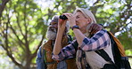 Elderly couple, bird watching and hiking with adventure, travel or trekking with binoculars. Outdoor, healthy old man or senior woman with fitness, interracial or woods with journey, nature or forest