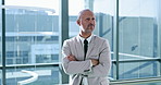 Arms crossed, leaning and thinking with business man at window of corporate office for planning. Future, idea and vision with serious employee in suit at workplace for development or problem solving