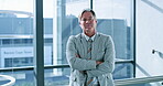 Arms crossed, experience and thinking with business man at window of corporate office for planning. Future, idea and vision with portrait of confident employee in suit at work for career development