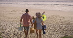 Holding hands, picnic and walking with family on beach together for bonding in summer holidays. Nature, love or vacation with mother, father and children on sand by ocean or sea for travel from back
