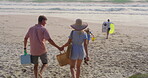 Back, holding hands and walking with family on beach together for picnic in summer holidays. Nature, travel or vacation with mother, father and children on sand by ocean or sea for weekend bonding