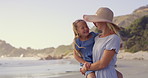 Beach, carry or laughing with mother and daughter walking outdoor for holiday, travel or vacation together. Love, morning or pointing with single parent woman and girl child by ocean for bonding