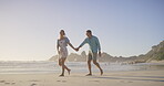 Couple, holding hands and walking on beach, love and talking on vacation for romance on honeymoon. People, trust and playful on tropical island, support and drag husband by waves on weekend date