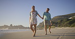 Couple, travel and walking by ocean, love and talking on vacation for romance on honeymoon. People, holding hands and playful on tropical island, support and drag husband by waves on weekend date