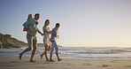 Family, talking or kids at beach walking at sunset for holiday or travel with boy, girl or parents. Siblings, mom or dad with children at sea on vacation together for wellness, joy or nature to relax