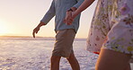 Beach, walking and legs of couple, holding hands and bonding in nature, adventure and romance on date. Love, man and relax with woman, travel and peace of ocean, together and getaway for lovers