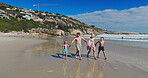 Family, kids and holding hands with walking on beach for summer vacation, tropical journey and bonding together. Parents, children and ocean water with holiday fun, calm morning and travel adventure