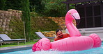 Holiday, relax and man in pool with float, smile and inflatable in water with flamingo at resort. Summer, weekend and happy guy swimming at hotel with adventure, celebration and fun vacation trip