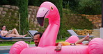 Holiday, relax and man in pool with inflatable, smile and float in water with flamingo at resort. Summer, weekend and happy couple swimming at hotel with adventure, celebration and fun vacation trip