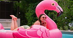 Holiday, relax and woman in pool with float, smile and inflatable in water with flamingo at resort. Summer, weekend and happy girl swimming at hotel with sunglasses, celebration and fun vacation trip