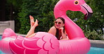 Summer, relax and woman in pool with float, smile and inflatable in water with flamingo at resort. Holiday, weekend and happy girl swimming at hotel with sunglasses, celebration and fun vacation trip
