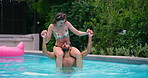 Holiday, pool party and couple with laughing, splash and bonding at hotel or resort. Swimming, shoulder carry and man with woman, water and balance for summer event, vacation celebration or fun