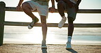 Beach, break and legs of friends on promenade together for summer holiday or vacation together. Relax, travel and trip with people sitting outdoor at ocean or sea for bonding, journey or wellness