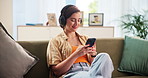 Home, smile and woman with smartphone for headphones, podcast and connection for streaming. House, female person and relax with mobile for application, online website and listening to music on couch