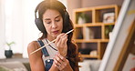 Woman, painter and wrist pain in studio with canvas, headphones and carpal tunnel in home. Person, injury and streaming subscription for music, fatigue and talent with creative project at apartment