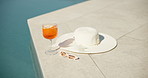 Swimming pool, cocktail and hat with sunglasses for vacation, summer holiday or relax outdoor. Water, alcohol glass and drink at hotel resort for tourism, travel and luxury with fresh lemon beverage