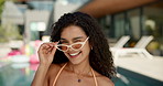Wink, fashion and face of woman by swimming pool for holiday, vacation and relax at resort. Sunglasses, happy and portrait of woman in swimsuit outdoors with confidence, pride and smile by water