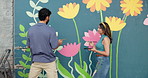 Wall art, people and painting mural with advice for creativity, community project and student hobby. Woman, man and friends for artist with diy decor, painter and flowers with expression outdoors