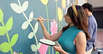 Wall art, project and painting mural with brush for creativity, community people and student hobby. Woman, man and friends for artist with diy decor, painter and flowers with expression outdoors