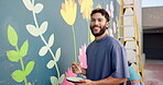 Wall art, man and painting mural with face for creativity, community project and student hobby. Guy, smile and brush for artist people with diy decor, painter and flowers with expression outdoors