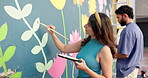 Wall art, people and painting mural with brush for creativity, community project and student hobby. Woman, man and friends for artist with diy decor, painter and flowers with expression outdoors