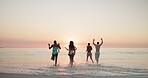 Beach, group and people with running on vacation, holiday weekend and having fun by sunset in summer. Back, friends and water splash in ocean for travel, adventure or freedom  with energy for playful