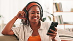 Black woman, phone and happy with headphones on sofa in home, music and relax in living room. African person, smartphone and listening with audio, streaming or subscription on mobile app at apartment