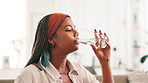 African woman, drinking water and glass on sofa for hydration, detox and thirsty in lounge. Person, liquid and wellness with gut health, benefits and relax on couch in living room at apartment
