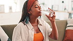 African woman, medicine and water on couch for health, supplements and vitamin c booster in lounge. Person, glass and drink with drugs, pills or pharmaceutical product for healing benefits in home