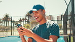Sports, laughing and man with phone on tennis court for social media, online chat and internet. Athlete, fitness and happy person on smartphone typing after training, exercise and workout for game