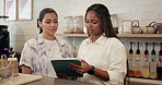 Tablet, women and baristas in coffee shop for planning online menu for small business. Digital technology, discussion and female waitresses with checking inventory at restaurant or cafeteria.