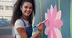 Face, woman and painting art on mural wall for creative design, flower decor and volunteer in city. Artist, happy girl and painter with brush for community service, charity and laughing with color