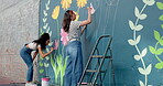 People, students and painting mural on wall of creative decoration, community project and artistic freedom. Women, artist and diy for public art, flower design and local culture for therapeutic hobby