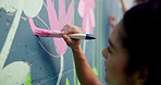 Art, woman and hand painting on wall in city for creative design, flower decoration and volunteer. Artist, closeup and painter outdoor with brush for community mural, floral color and charity project
