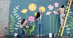Wall art, women and painting mural with ladder for creativity, community project and student hobby. Girl, friends and people for artist with diy decor, painter and flowers with expression outdoors