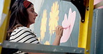 Flower, woman and creative painting on wall in city with artist for decor or volunteer. Art, painter and outdoor with brush for environment activist, wind and sustainable hobby on mural with ladder