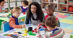 Painting, teacher and children with artwork, classroom and students with creativity in daycare and growth. Talking, woman and teaching kids for development, youth and learning with color in preschool