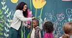 Teacher, mural and height with children and wall for friends, painting or measuring growth. Flowers, learning and kindergarten street art with group of kids and woman for education and drawing
