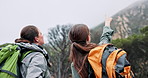 Hiking, woman and friends pointing to mountain for sightseeing, nature scenery and travel adventure. Trekking, back of people and backpack with holiday exploration, view discussion or tourism journey