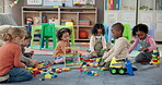 Kids, students and play with blocks in classroom of learning, problem solving and creative activity. Children, toys and floor for education game, puzzle solution and motor development in kindergarden