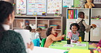 School, desk and teacher with children in classroom for lesson, learning and education. Students, teaching and educator with papers for grading and kids for early development, knowledge and progress