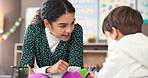 Education, learning or study with student and teacher in classroom together for development. Conversation, lesson or teaching with boy child and woman at desk in school for academic scholarship