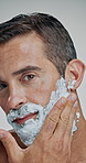 Man, face and beard with cream for shave, hair removal or epilation on a white studio background. Portrait, male person or model with cosmetics, foam or soap for hygiene, grooming or facial treatment
