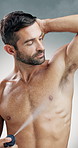 Happy man, spray or deodorant with hygiene for fragrance, scent or aroma on a studio background. Male person, antiperspirant or model applying perfume with smile for armpit, odor mask or body cologne