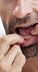 Closeup, man and teeth with dental floss in studio for oral care, hygiene or cavity on a white background. Male person, mouth or model with string or thread for cleaning gums, food or plaque removal