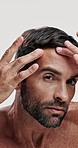 Man, face and check skin for cosmetic care, acne or pimple with grooming, selfcare and hands on white background. Serious, antiaging and skincare with inspection, portrait and dermatology in studio